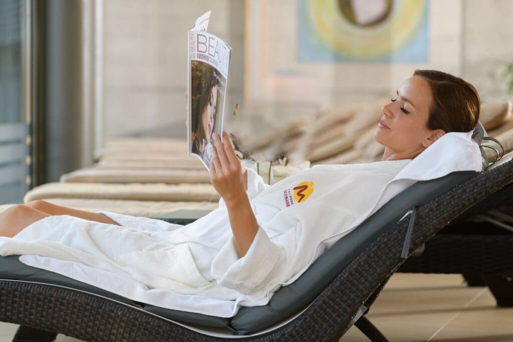 eine Dame relaxed am Liegestuhl mit einer Zeitschrift in der Hand