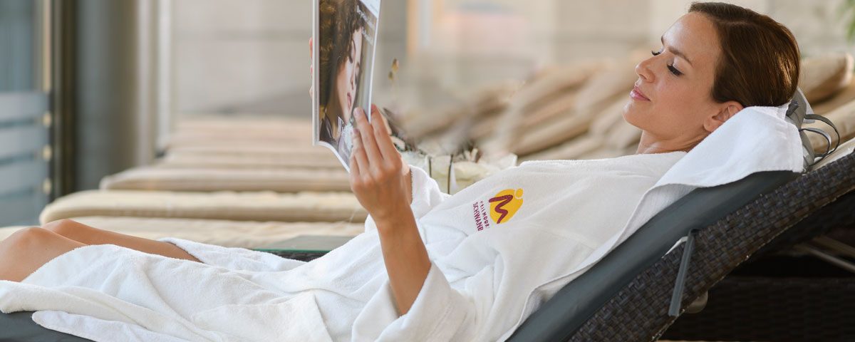 eine Dame relaxed am Liegestuhl mit einer Zeitschrift in der Hand
